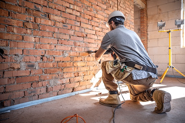 A builder works with a drill at a construction site.